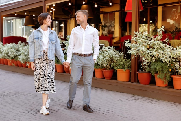 Un par de 30 años van juntos y se dan la mano en un paseo