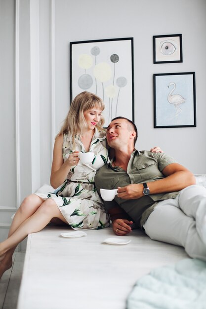 Par alegre sentado em casa e tomando café juntos