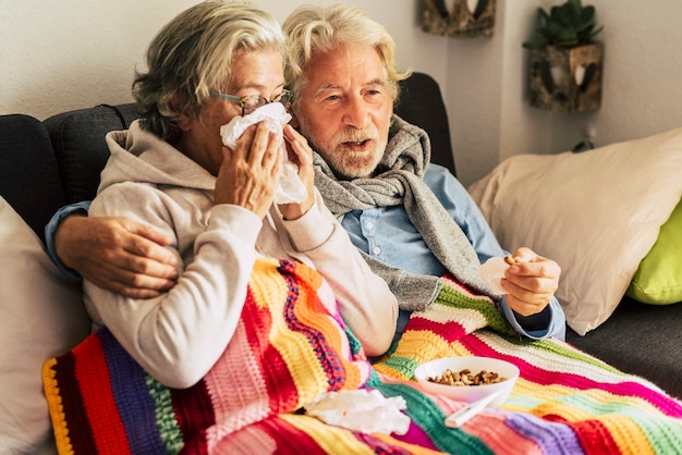 Par de ancianos ancianos en casa con enfermedad de frío de invierno estacional enfermedad sentarse en el sofá juntos para siempre