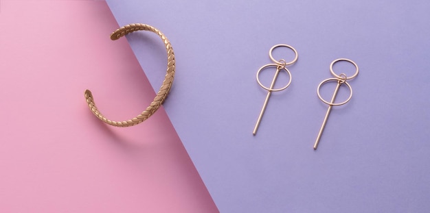 Par de aretes de diseño geométrico y pulsera sobre fondo de colores pastel con espacio de copia