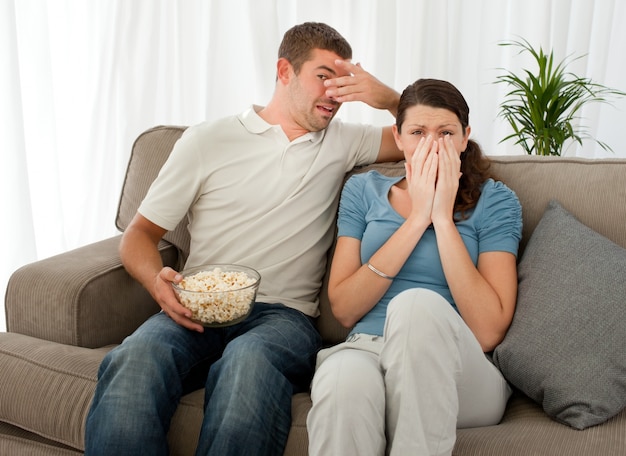 Par asustado comiendo palomitas de maíz mientras mira una película de terror