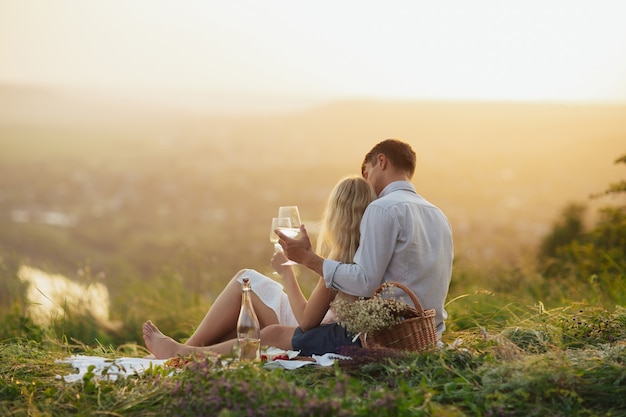 Par bebiendo vino en un picnic en un campo