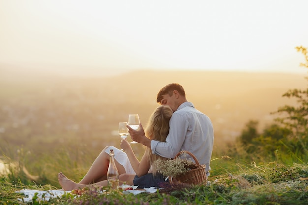 Par bebiendo vino en un picnic en un campo