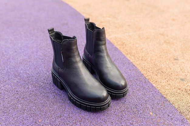Un par de botas de cuero negro descansa sobre una alfombra morada.