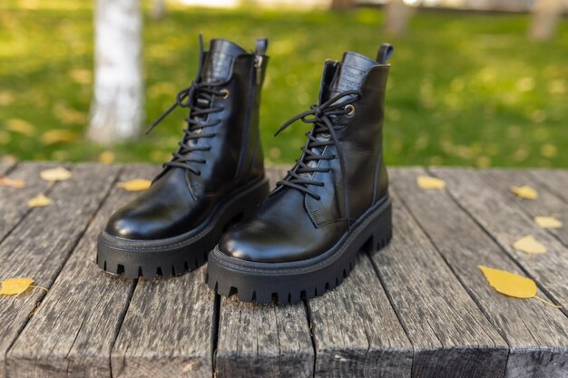 Un par de botas de cuero negro están sobre una superficie de madera.