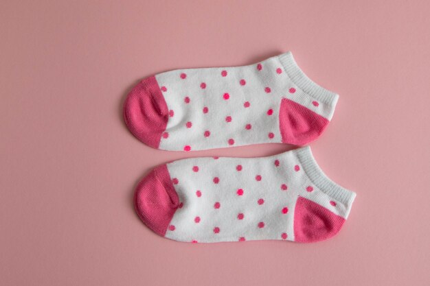 Un par de calcetines blancos para niños con calcetines y tacones rosados, con puntos rosados,