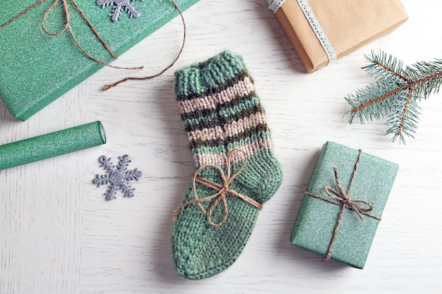 Par de calcetines tejidos con regalos envueltos para Navidad en mesa de luz