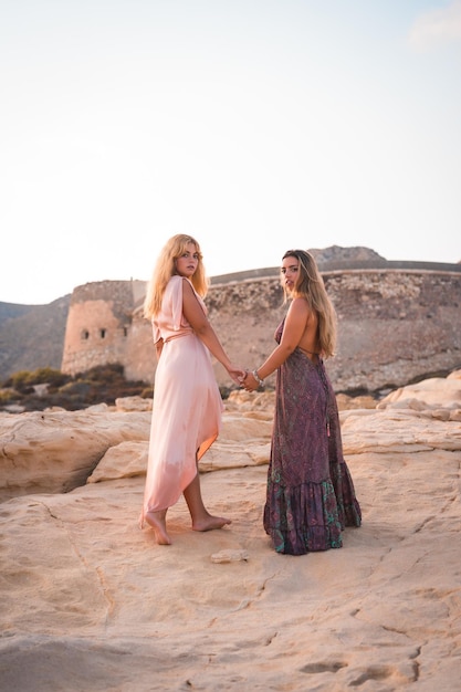 Un par de chicas caucásicas con vestidos rosas en verano en el Playazo de Rodalquilar