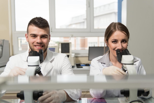 Par de científicos mirando en un microscopio