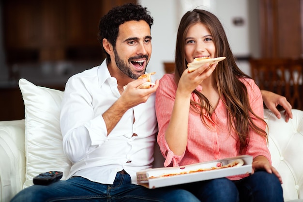 Par, comendo pizza, e, televisão assistindo