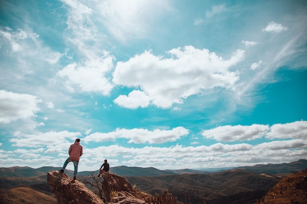 Par de amigos do sexo masculino admirando a vista deslumbrante no final das falésias nas montanhas