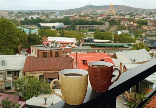 Par de canecas de café quentes na varanda com vista aérea de Tbilisi na Geórgia