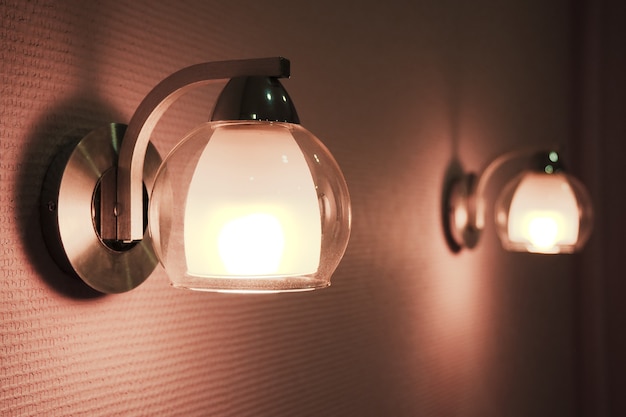 Par de lâmpadas acende no quarto. A imagem discreta de duas lâmpadas noturnas.