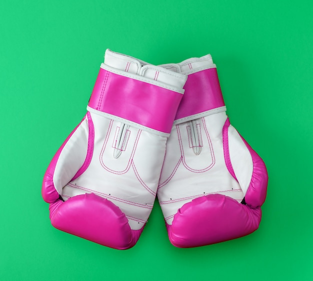 Par de luvas de boxe de couro rosa-branco sobre um fundo verde