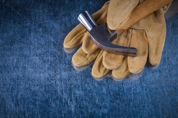 Par de luvas de proteção de couro com martelo de metal no conceito de construção de fundo metálico riscado