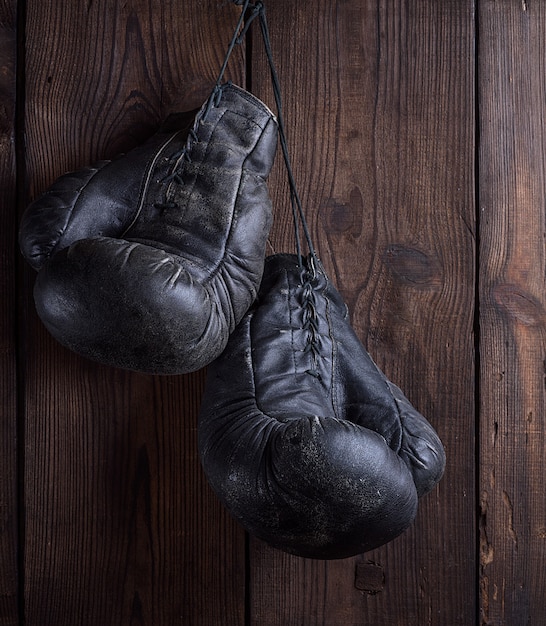 Par de muito velhas luvas de boxe de couro preto gasto pendurado na unha