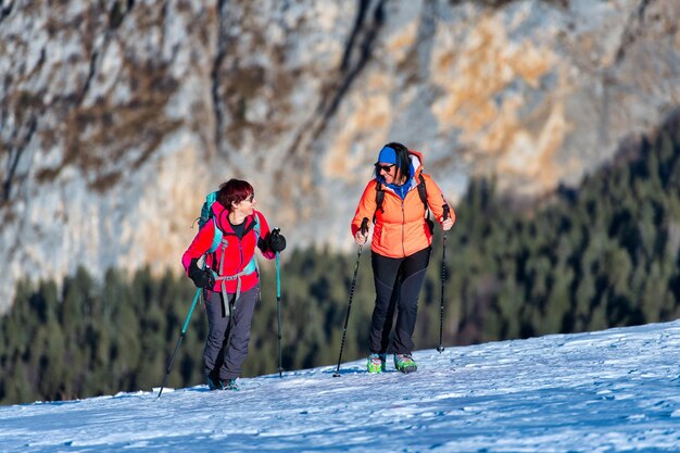 Par de mulheres amigáveis durante uma caminhada na montanha na neve