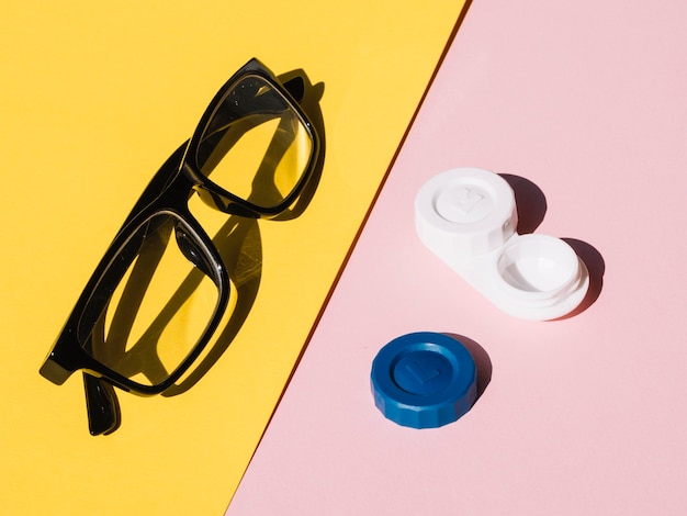 Foto par de óculos e lentes de contato em fundo amarelo e rosa