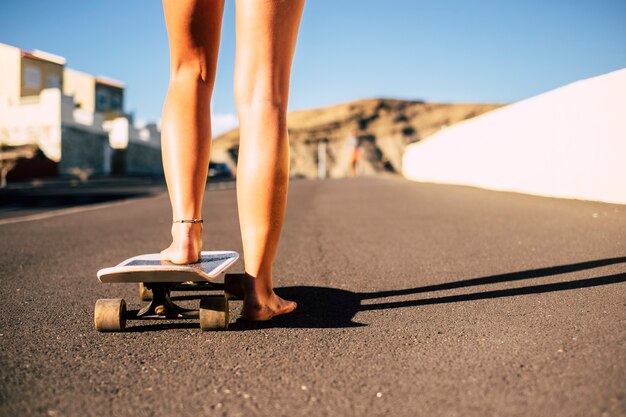 Par de pernas descalças jovem pronta para começar com o skate no asfalto