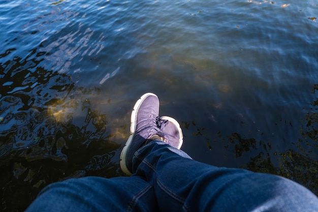 Par de pés relaxando à beira de um lago em uma doca de madeira. P