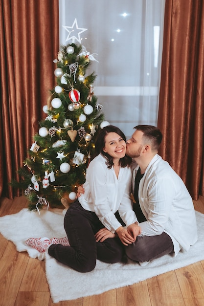 Par disparar delante del árbol de Navidad decorado con tarjeta de regalo de espacio de copia