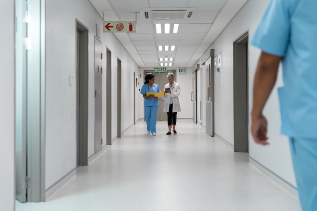 Un par diverso de doctoras caminando por el pasillo del hospital discutiendo