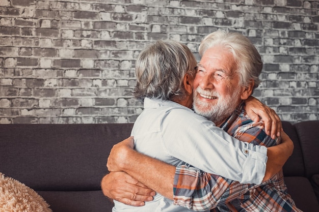 Un par de dos ancianos se abrazan juntos divirtiéndose y cuidándose unos a otros en casa en el sofá Personas maduras enamoradas disfrutando de la vida