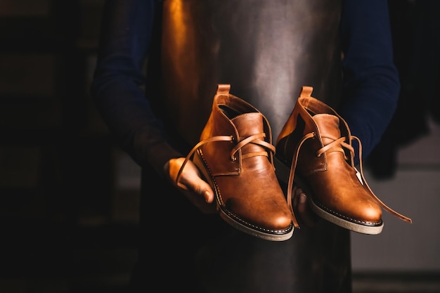 Un par de elegantes zapatos de cuero acabados en manos de un maestro con un delantal de cuero amarillo