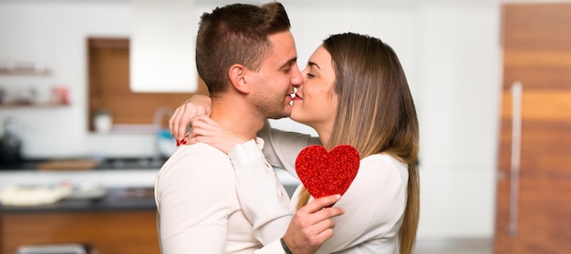 Par, em, dia valentine, segurando, um, coração, símbolo, e, beijando, em, um, casa