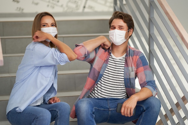 Par de estudiantes con máscaras relajantes en el campus