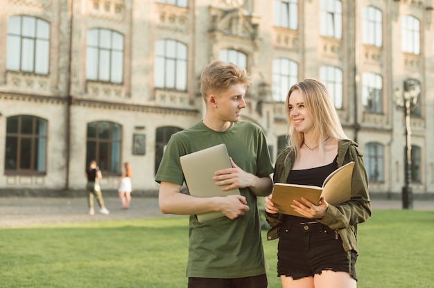 Par de estudiantes de pie cerca de la universidad