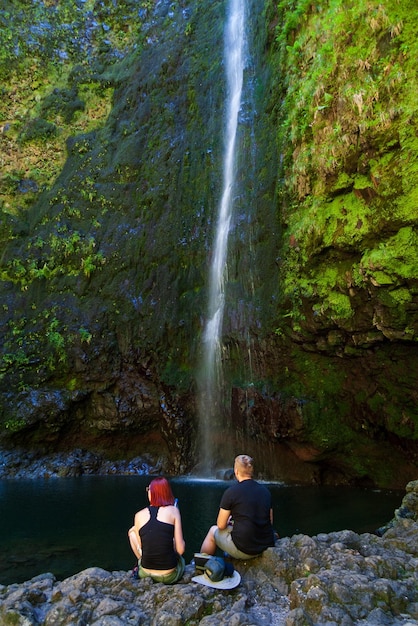 Un par de excursionistas descansan frente a una cascada en levada 25 fontes Madeira Portugal