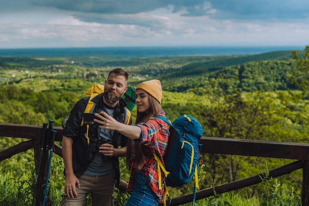 Un par de excursionistas tomándose selfie con un teléfono inteligente mientras pasan el día en la naturaleza