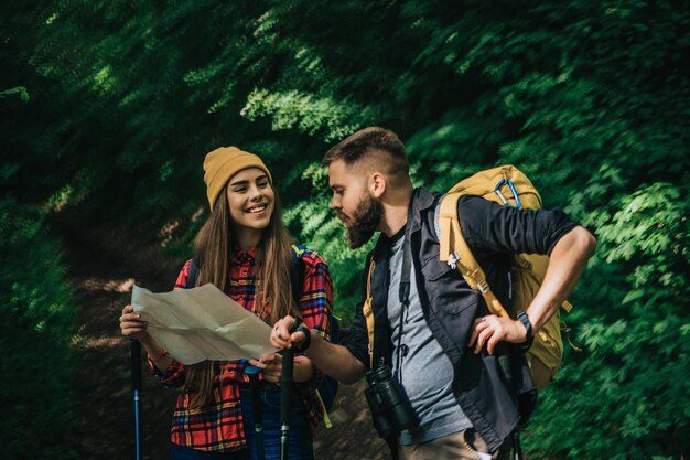 Un par de excursionistas usando bastones de trekking y un mapa mientras usan mochilas