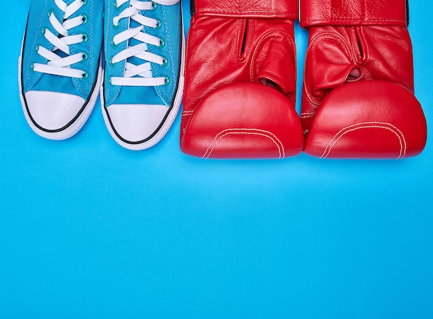 Par de guantes de boxeo rojos y zapatillas de deporte azules.