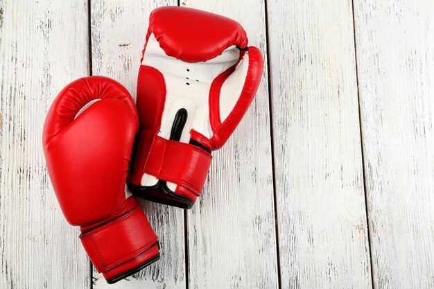 Par de guantes de boxeo sobre fondo de madera de color