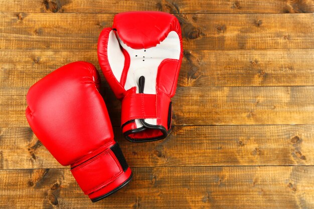 Par de guantes de boxeo sobre fondo de tablas de madera