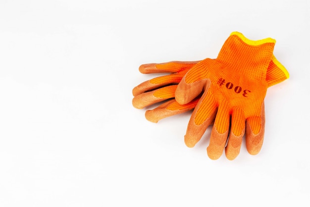 Un par de guantes protectores naranjas para trabajos de jardinería, construcción y reparación en blanco