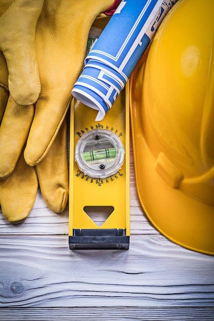 Par de guantes de seguridad casco de construcción blueprints nivel de construcción en tablero de madera