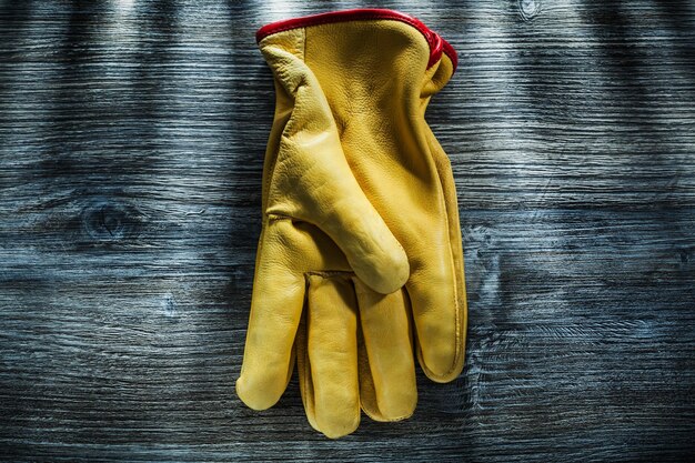 Par de guantes de seguridad de cuero sobre tablero de madera.