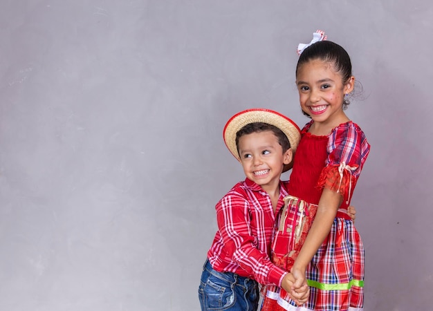 Foto par de hermanos vestidos con ropa tradicional para bailar festa junina