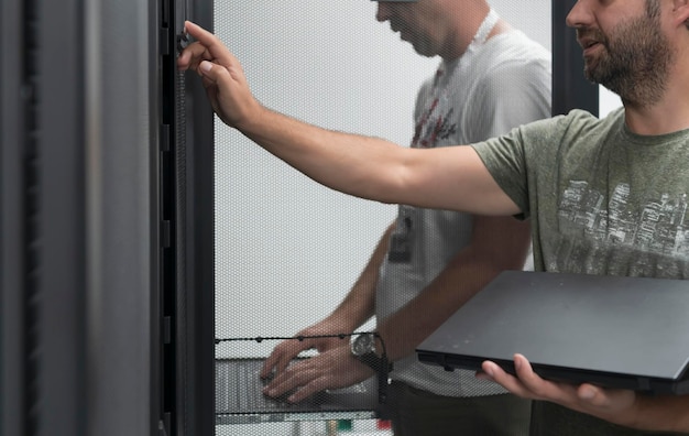 Un par de ingenieros de servidores cooperan en centros de datos de alta tecnología. El equipo de técnicos actualiza el rendimiento del sistema de inspección de hardware en la sala de servidores de supercomputadoras o en la granja minera de criptomonedas.