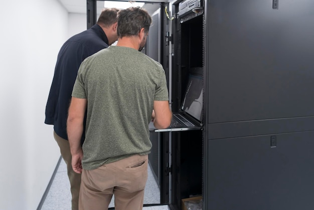 Un par de ingenieros de servidores cooperan en centros de datos de alta tecnología. El equipo de técnicos actualiza el rendimiento del sistema de inspección de hardware en la sala de servidores de supercomputadoras o en la granja minera de criptomonedas.