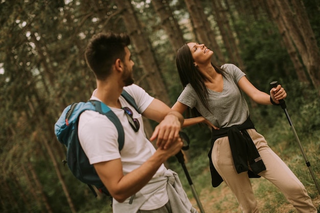 Un par de jóvenes excursionistas con mochilas caminan por el bosque