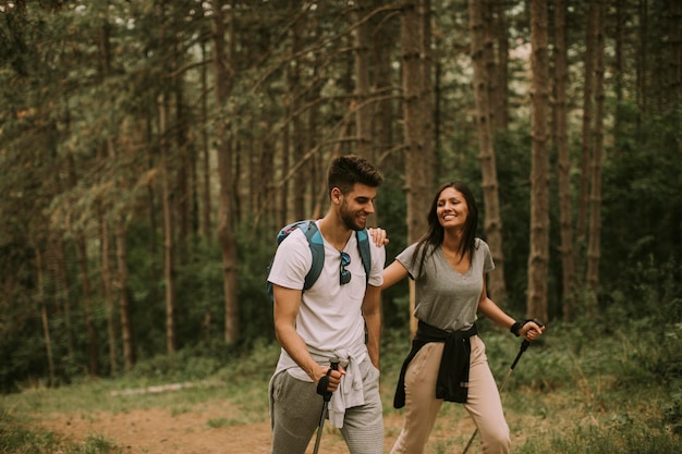 Un par de jóvenes excursionistas con mochilas caminan por el bosque