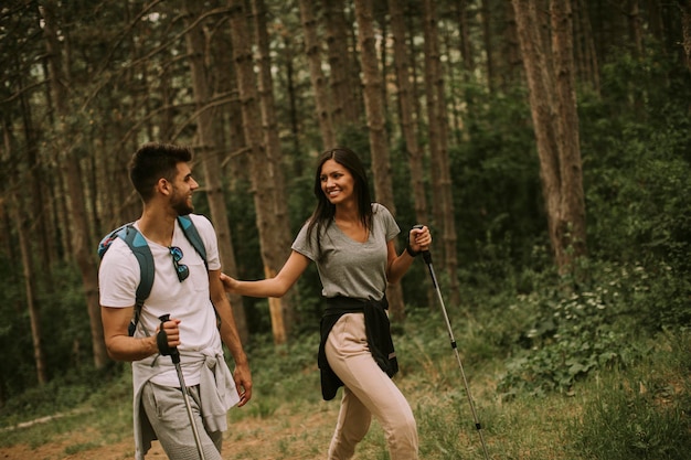 Un par de jóvenes excursionistas con mochilas caminan por el bosque