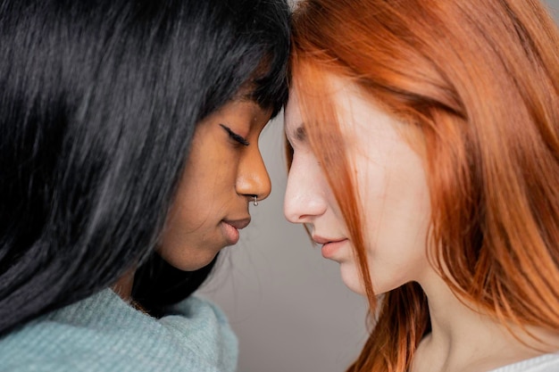 Un par de jóvenes lesbianas de diferentes etnias cabeza a cabeza mientras miran hacia abajo Mujer caucásica y novia afroamericana Concepto multicultural Lgbtq y derechos de pareja gay