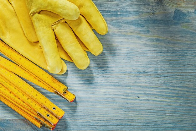 Par de medidores de madera de guantes de seguridad de cuero en el concepto de construcción de tableros de madera