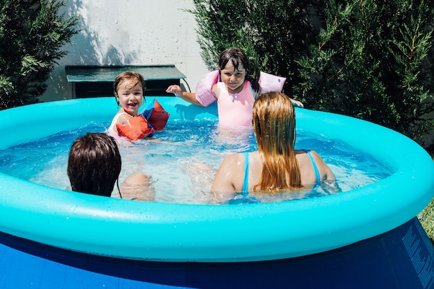 Foto un par de mujeres lesbianas se bañan en la piscina con sus hijas con manguitos en verano