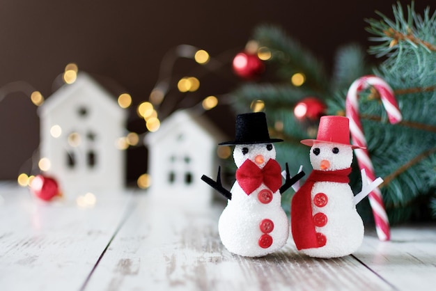 Un par de muñecos de nieve parados en un piso de madera cerca del árbol de Navidad